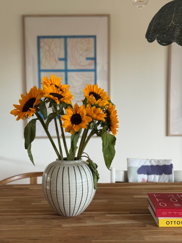 Sunflowers in a vase on a table evoking the feeling of bringing the outside in which helps bring home the feeling of being at the beach.