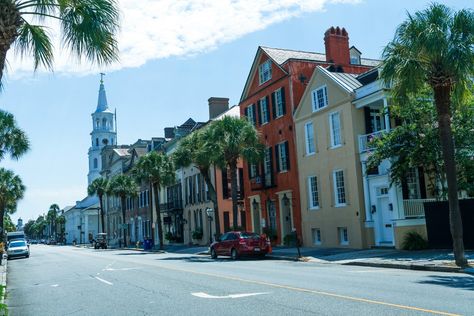 Historic Charleston, South Carolina streetscape with colorful historic homes, palm trees, and a church steeple rising above the downtown skyline.
